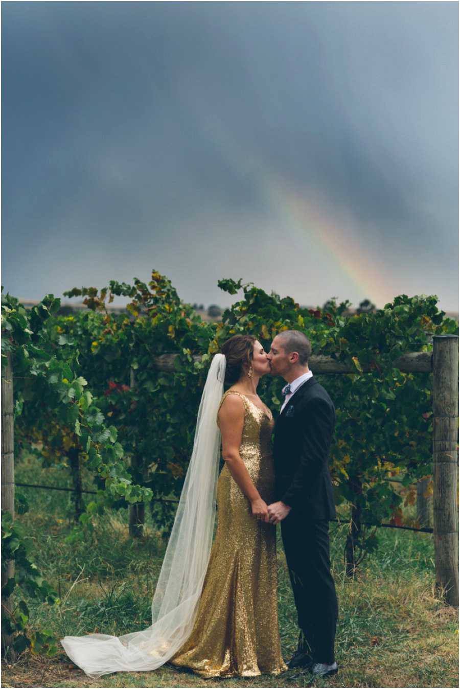 Yarra Valley wedding venues - Bride and Groom kissing with rainbow