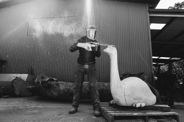 black and white picture of a sculture using his chainsaw to make wooden art