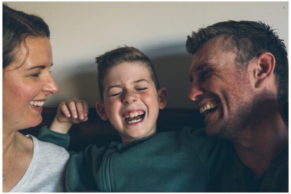 Little boy laughing hard in his parents arms