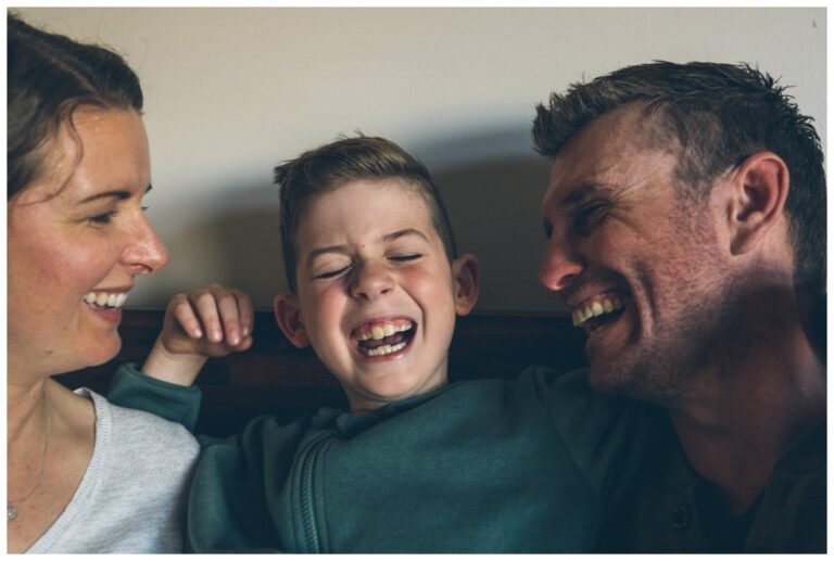 Little boy laughing hard in his parents arms