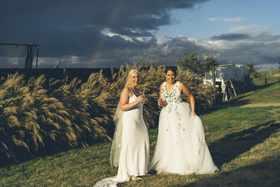 Brides standing together under rainbow sky during Yarra Valley wedding