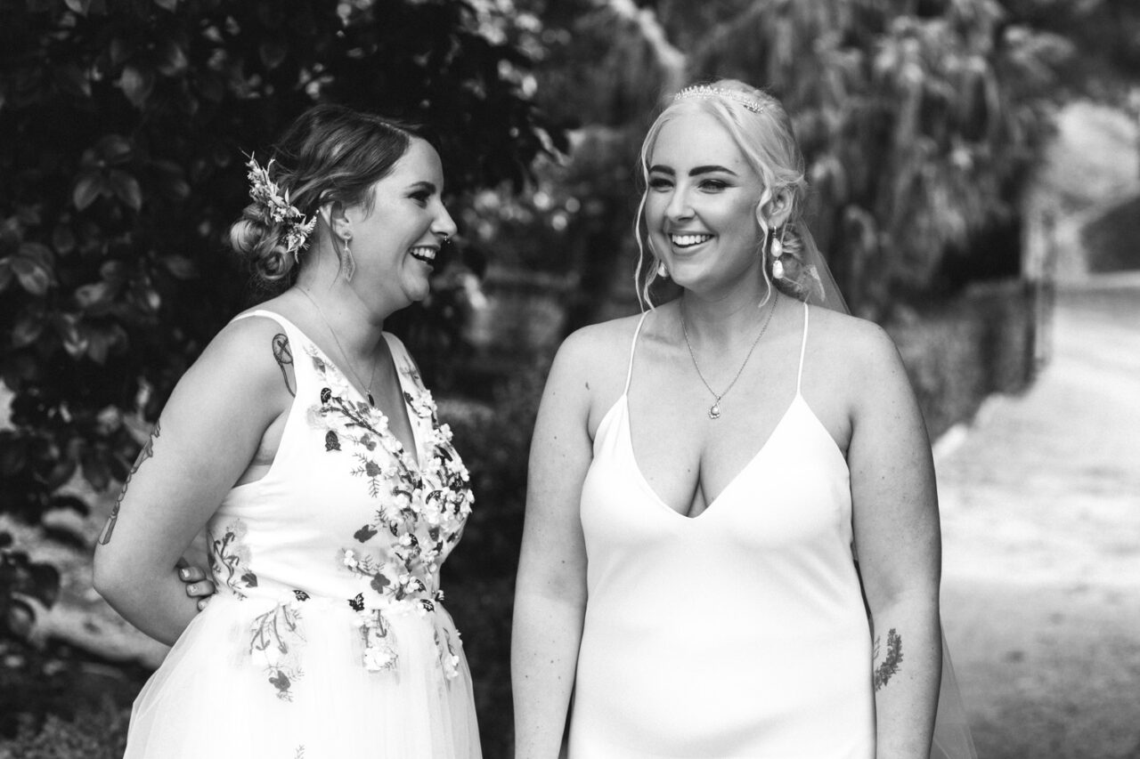 Brides laughing together on garden pathway at Alowyn Gardens wedding