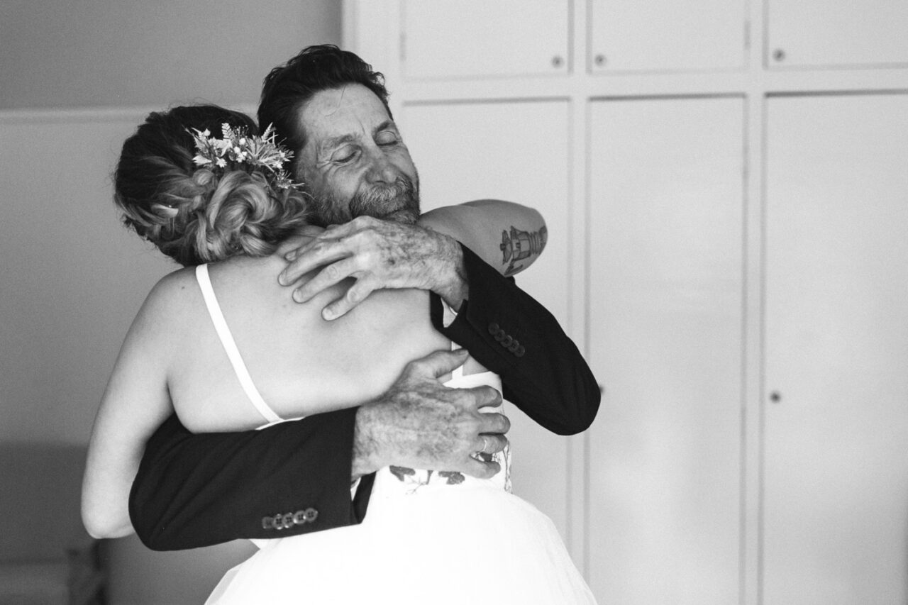 Father hugging bride during emotional wedding morning moment in black and white