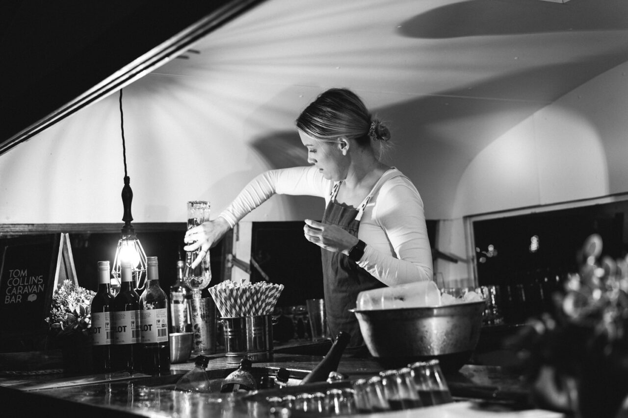 Bartender preparing drinks at wedding bar in candid black and white moment