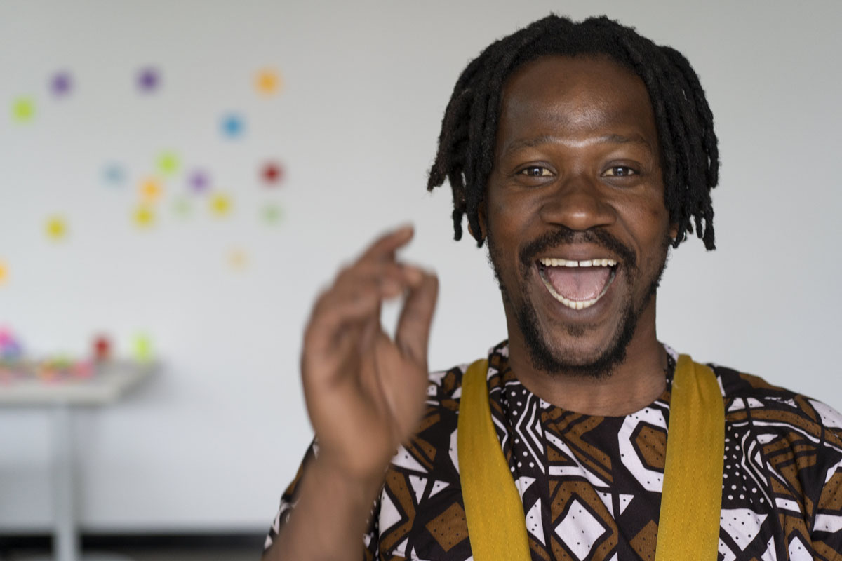 Jamaican man drumming, smiling at the camera at a corporate event