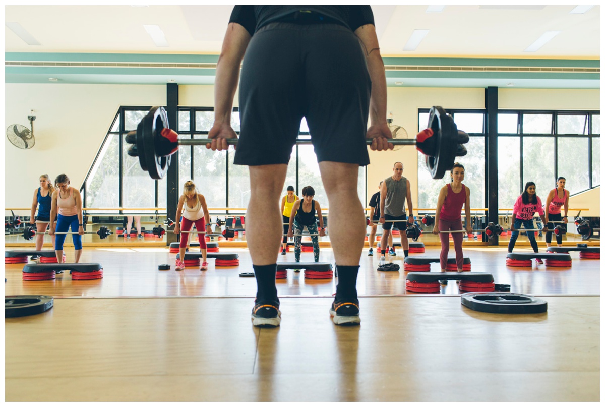 Shot of an instructor doing a weights class from behind him