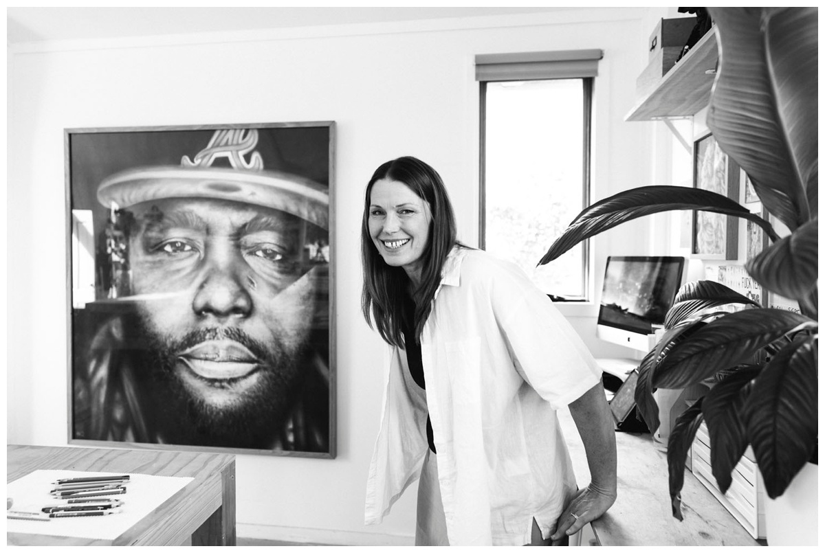 Fine art artist smiling at camera with art in back ground