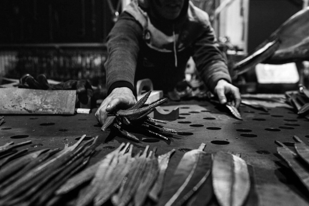 Line of forged steel feathers laid out in the workshop.