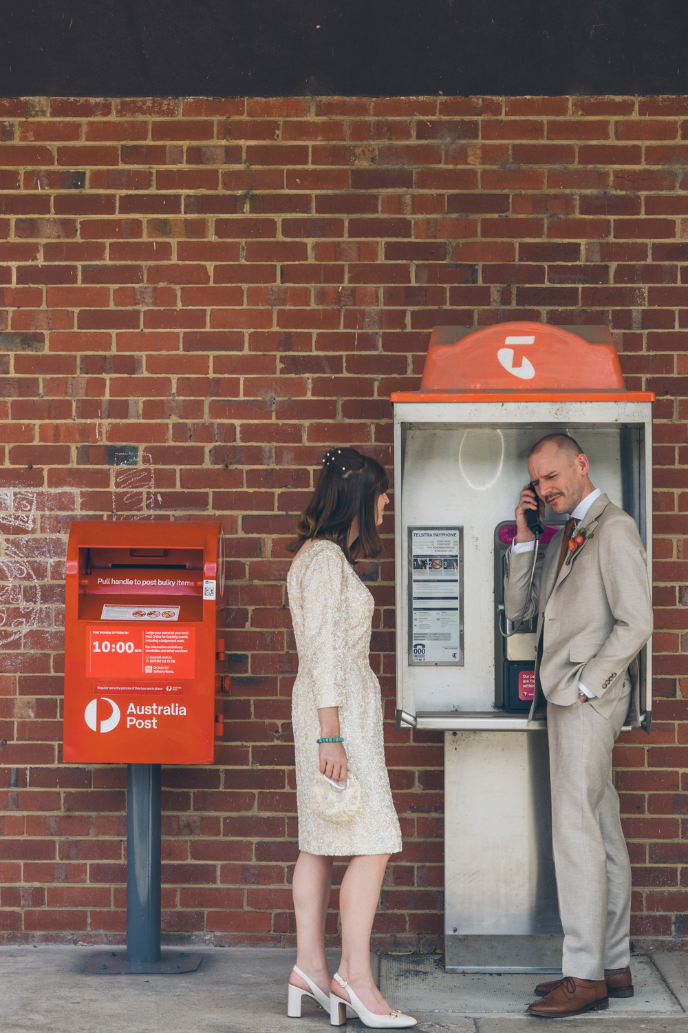 Bride and groom standing beside red post box and Telstra phone booth in small country town