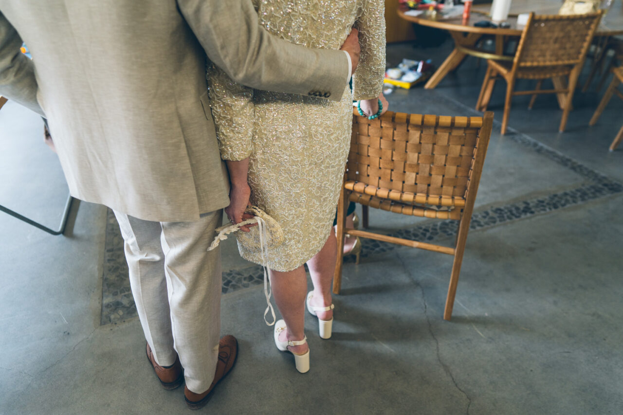 Close-up of a bride and groom standing together inside, holding hands and embracing during a quiet moment before the ceremony.
