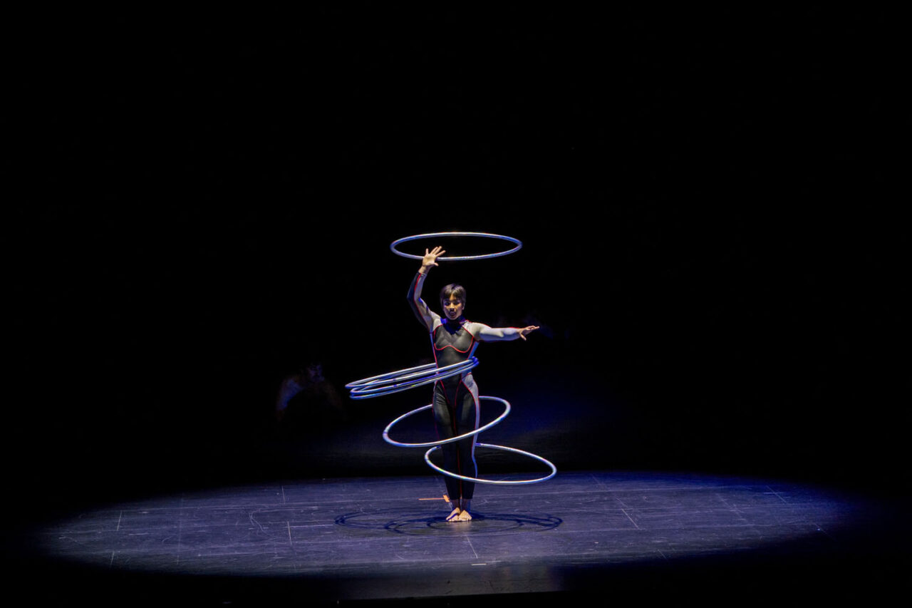 Circa performer spins multiple hula hoops under a spotlight during Duck Pond at The Round, Melbourne — a blend of strength, rhythm and circus artistry.