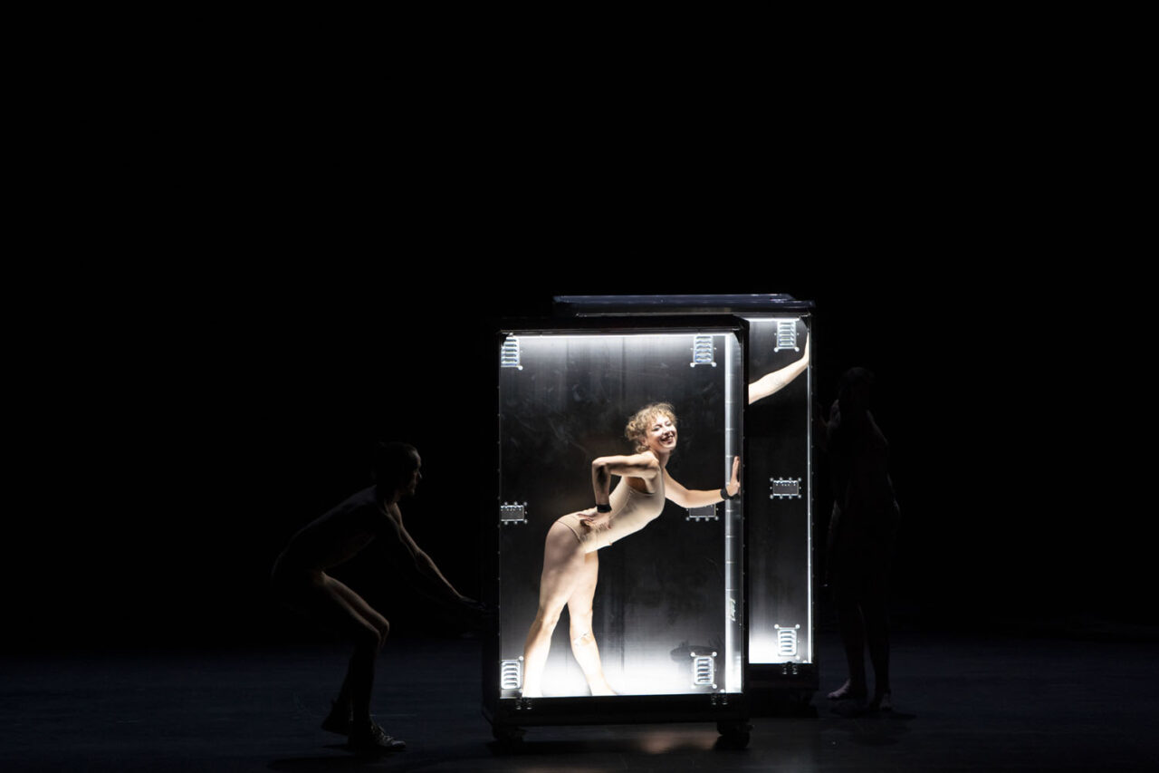 Performer inside a lit transparent box on a dark stage during Circa’s Duck Pond at The Round Melbourne, photographed by Lauren Marshall.