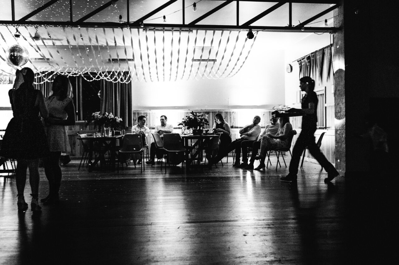 Guests relax and chat inside the hall under string lights as the night winds down