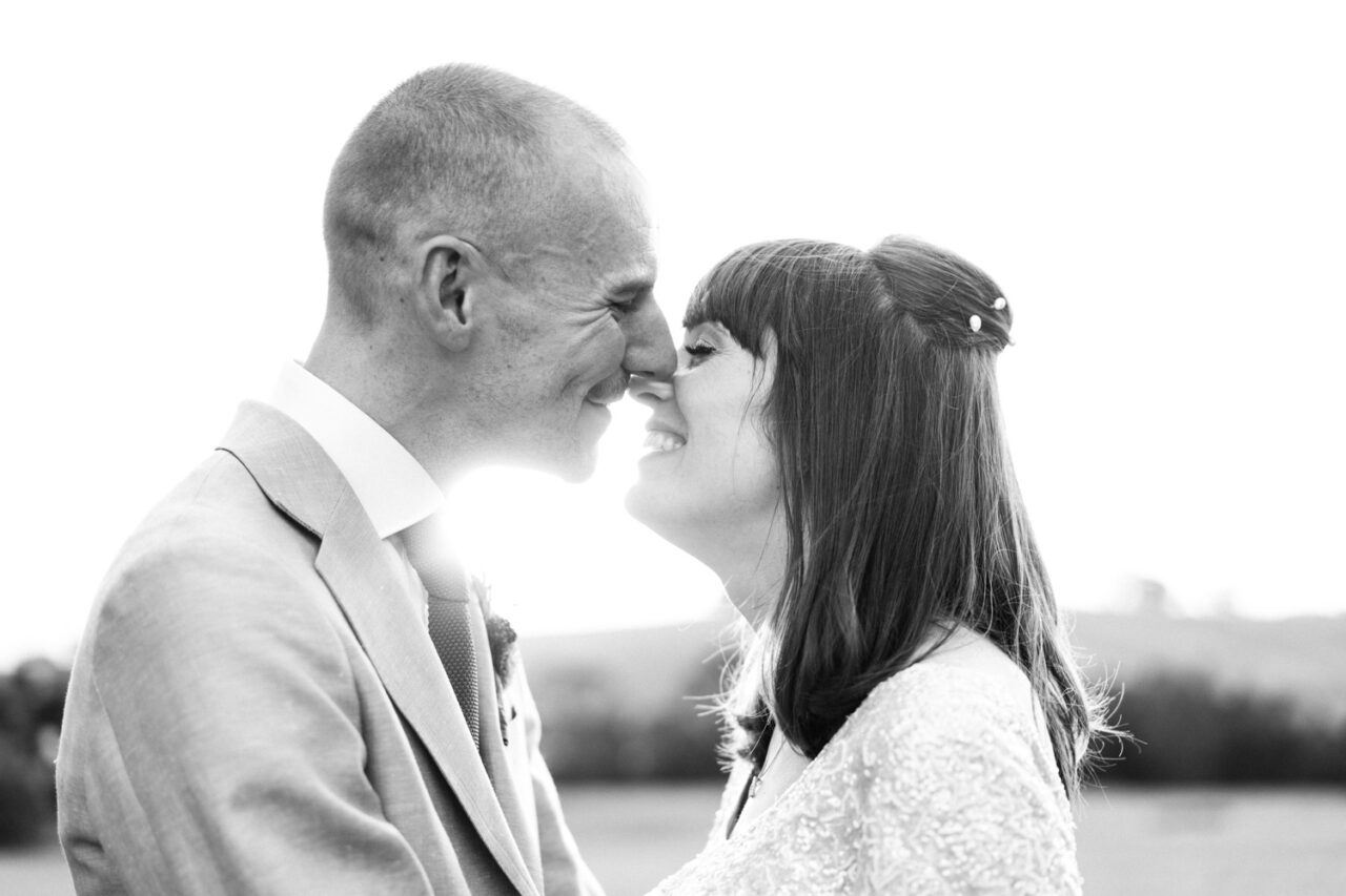 Bride and groom touching noses and smiling in soft natural light