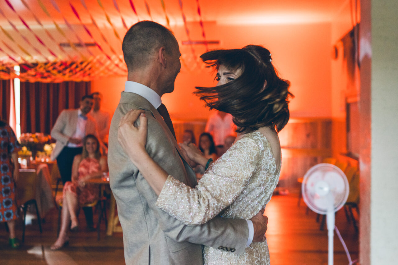 Bride and groom dancing under warm orange lights at their wedding reception