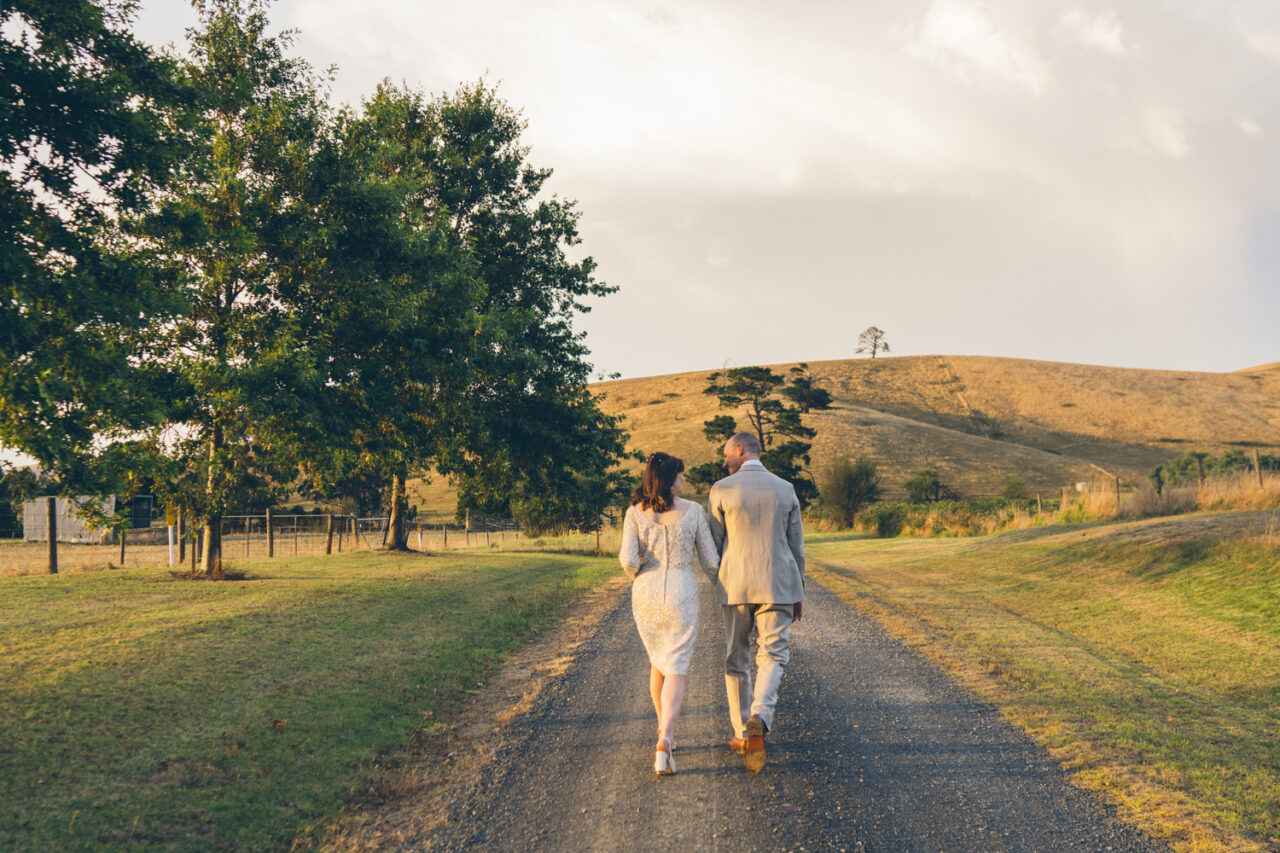 Couple walking along a country road at sunset after their wedding