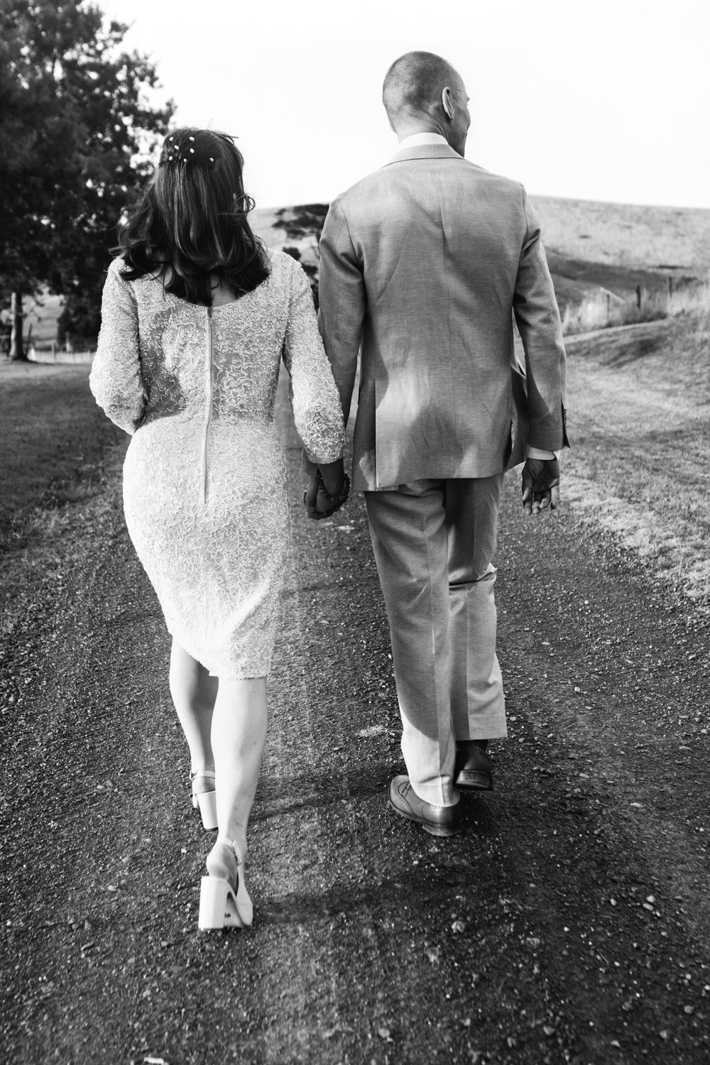 Bride and groom walking hand in hand down a country road after their wedding