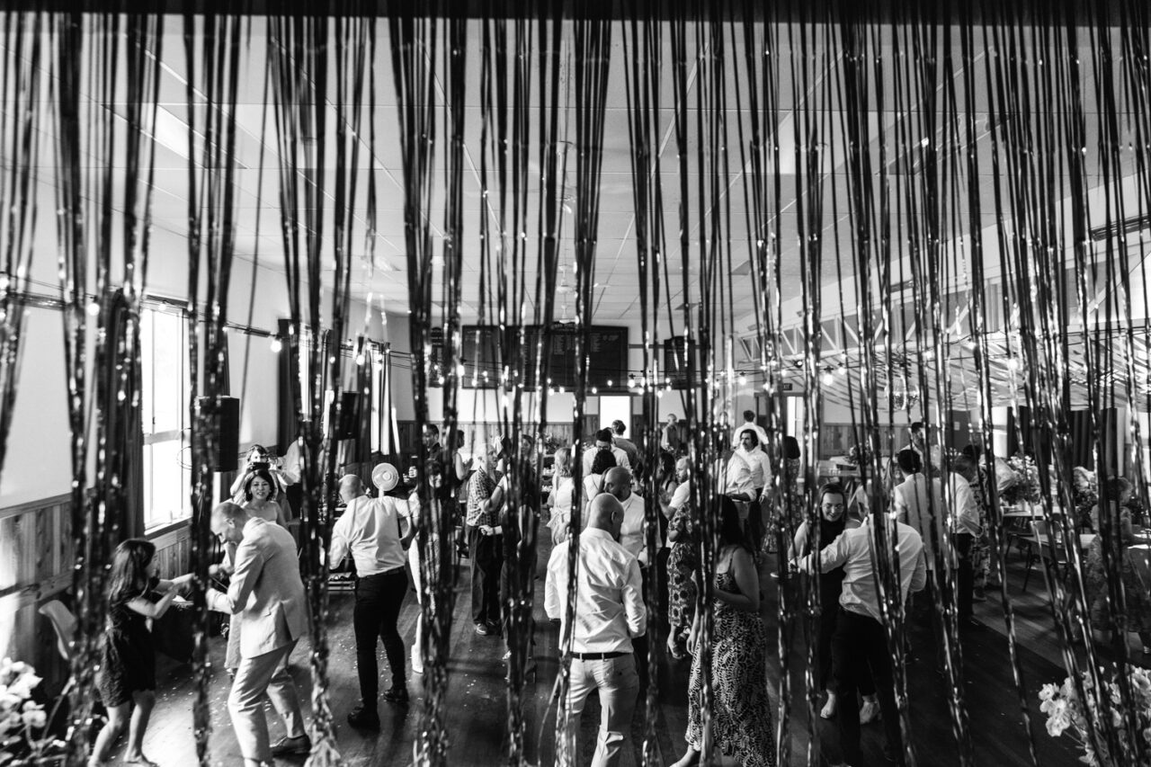 Guests dancing beneath streamers and disco lights inside the wedding hall.