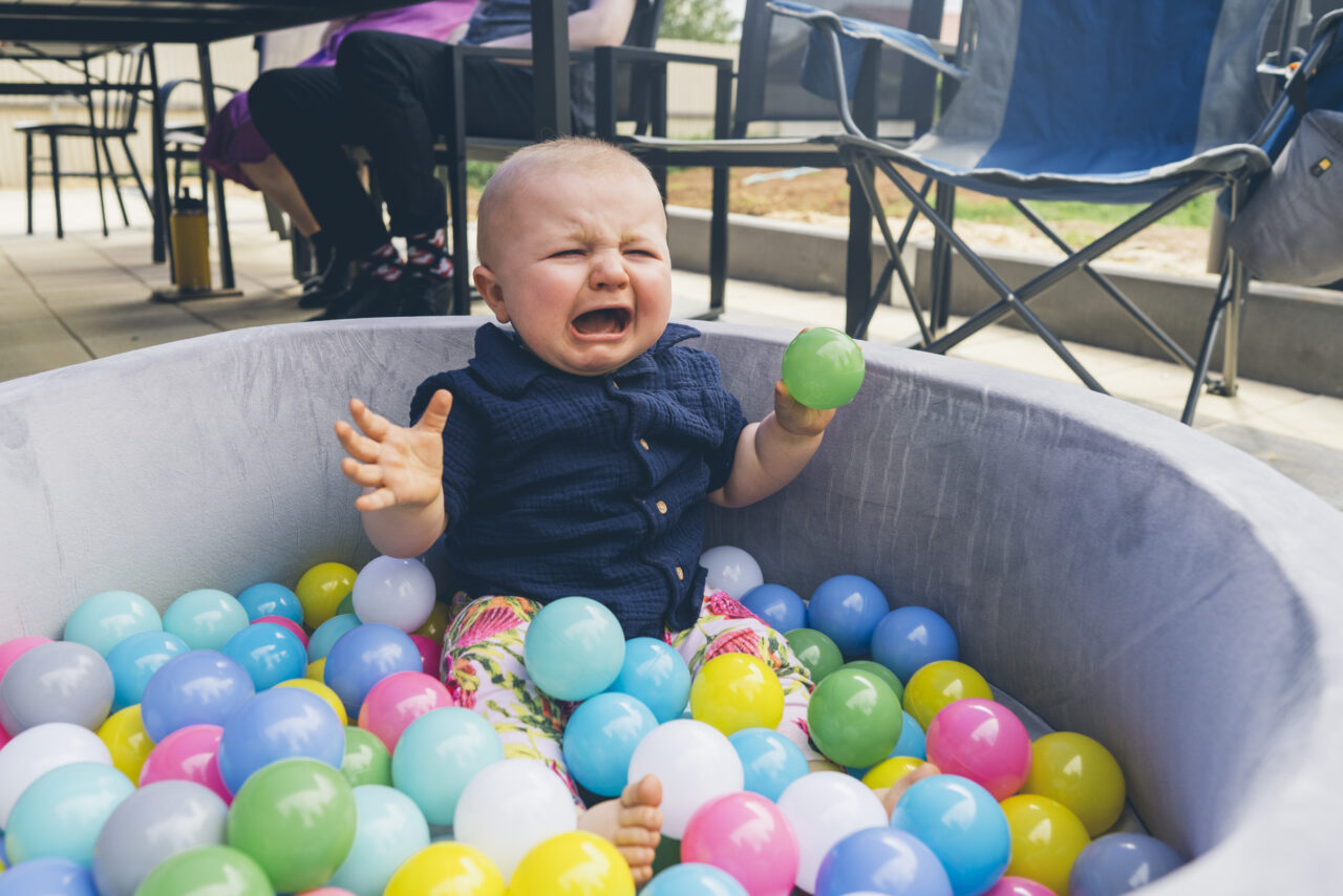 Honest storytelling moment of a baby crying in a ball pit during a candid family photo session on the Surf Coast