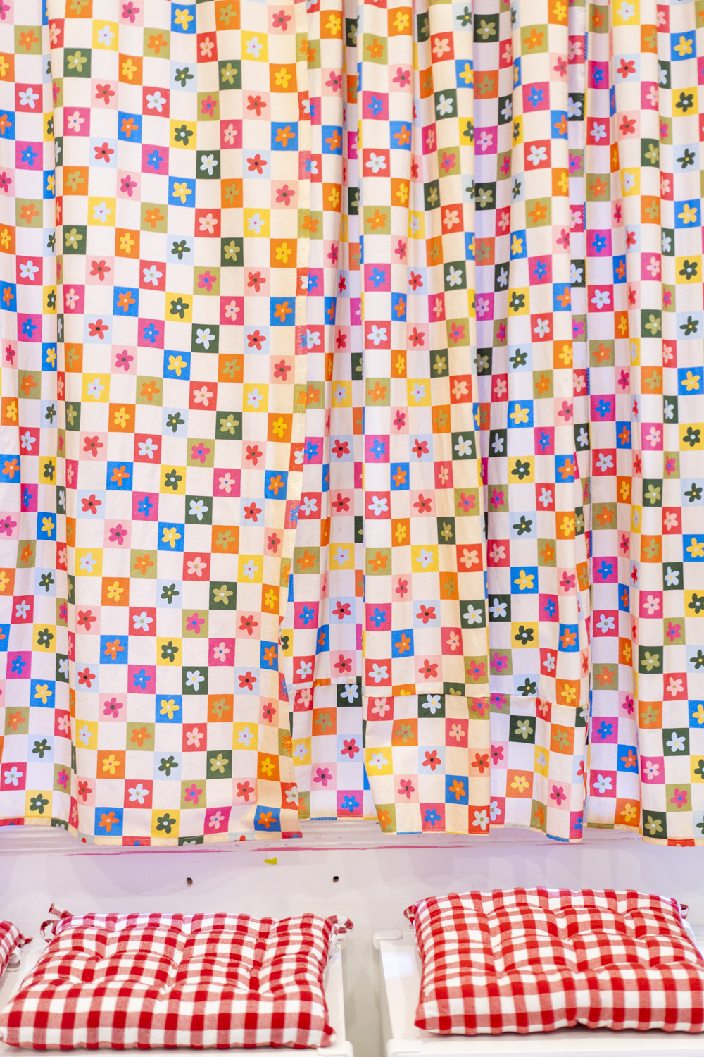 Colourful patterned curtain with red checkered cushions inside Beurre Cakes, captured as interior detail for documentary brand photography.