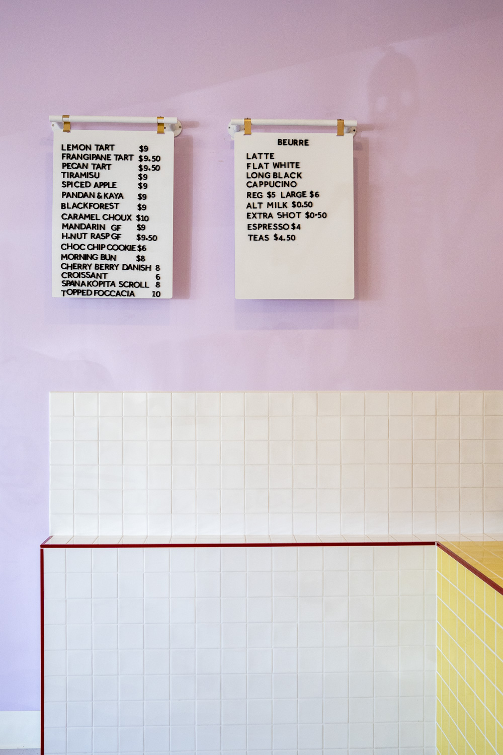 Menu boards hanging on the lilac wall inside Beurre Cakes, photographed as part of documentary brand photography for a creative small business.