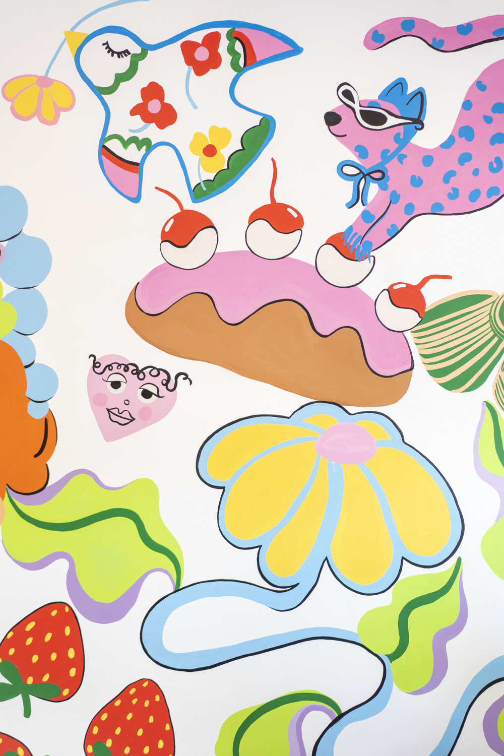 Close up of the colourful hand painted mural inside Beurre Cakes featuring a bird, cherries and bright character illustrations.