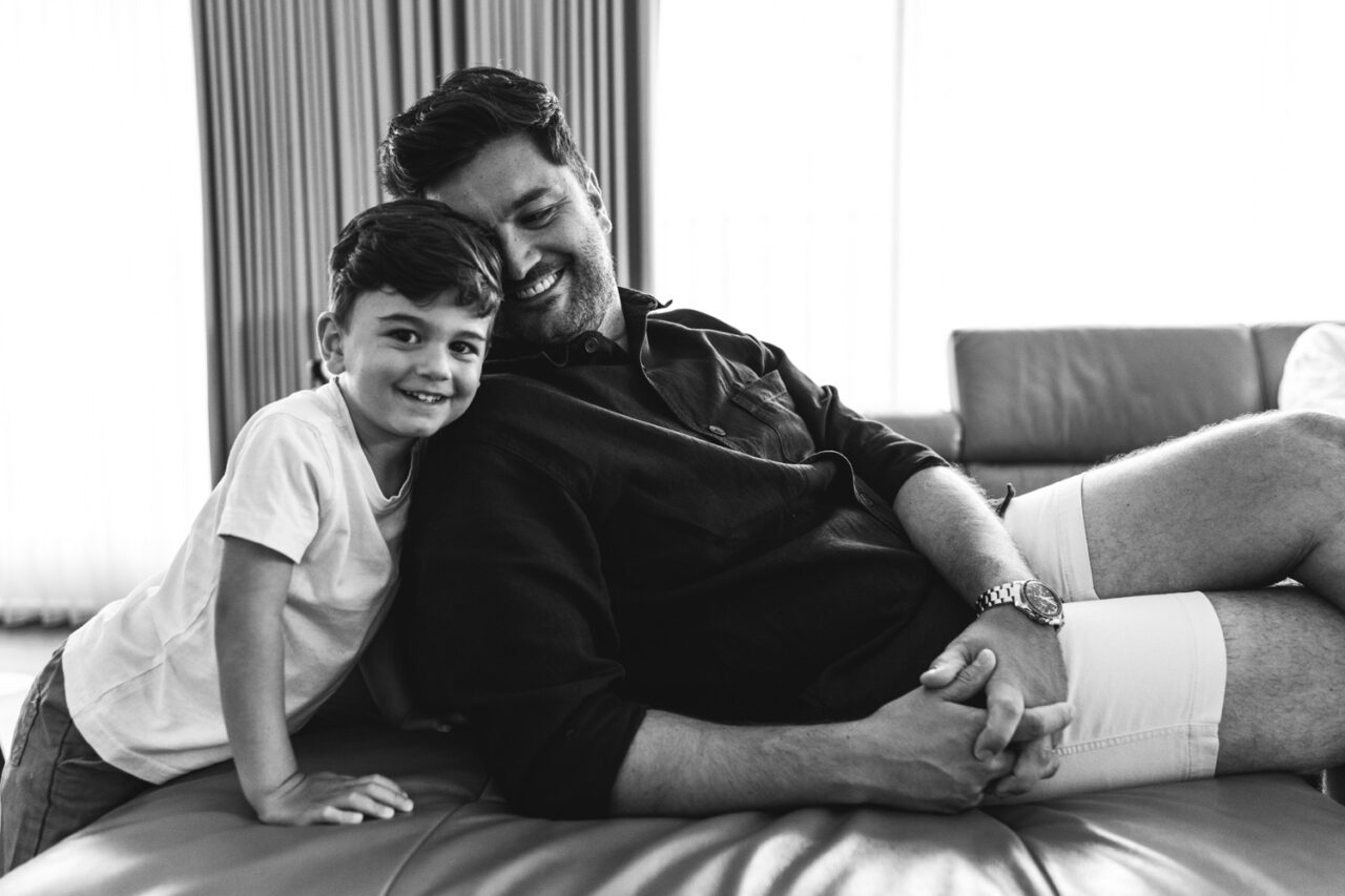 Candid moment of a father and son laughing together during an in-home summer storytelling session on the Surf Coast