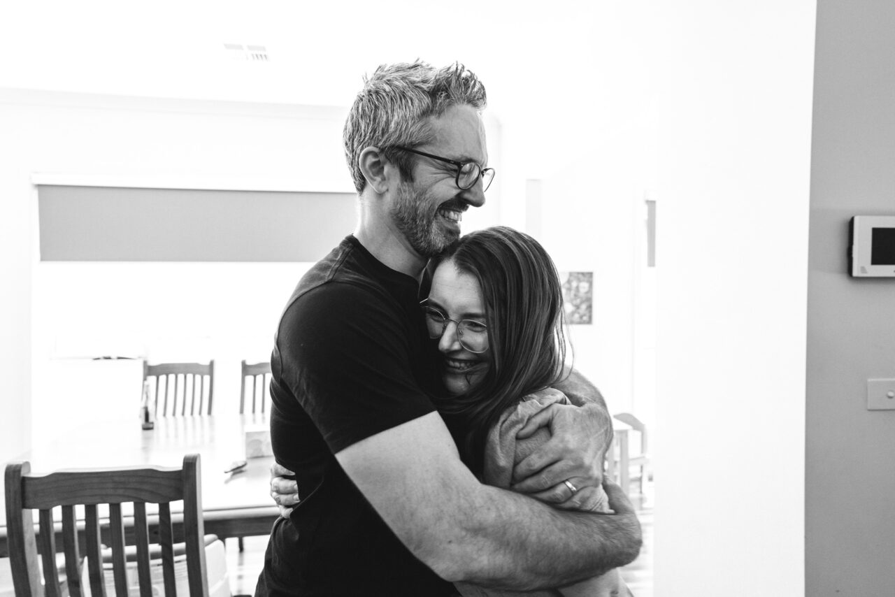 Couple sharing a genuine hug at home during a relaxed summer storytelling photo session