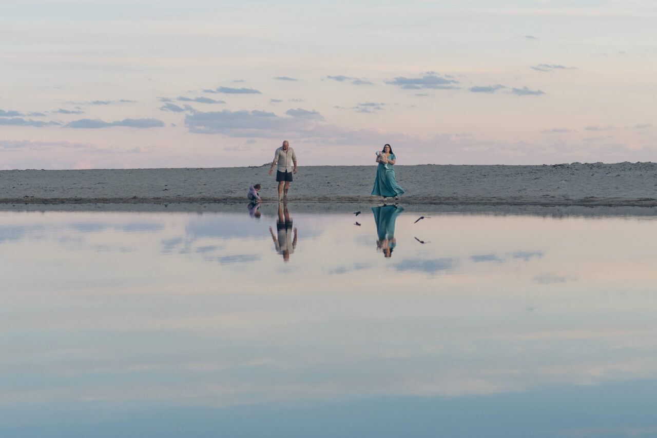 Family walking by the water at sunset, reflected in calm shallows during a candid summer photography session Surf Coast