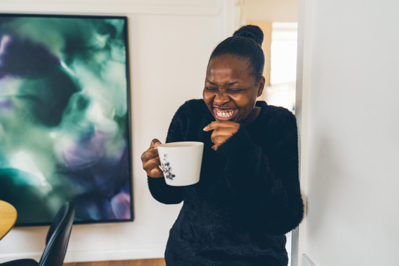 Woman laughing while holding a mug of tea