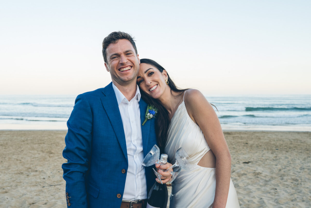 Wedding couple celebrating with champagne on the beach, relaxed Surf Coast wedding moment