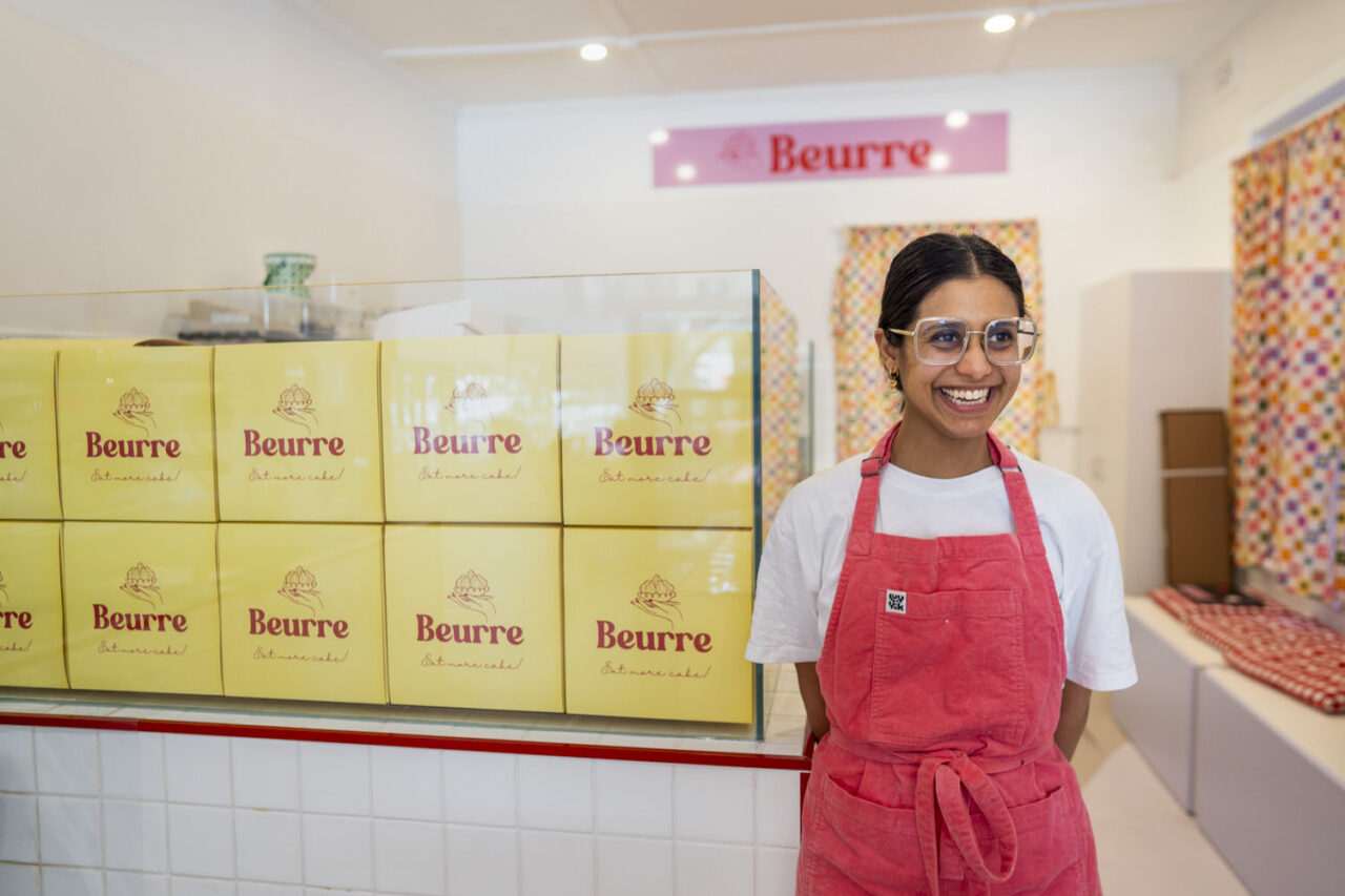 Portrait of Beurre Cakes owner standing behind bakery counter with cake boxes