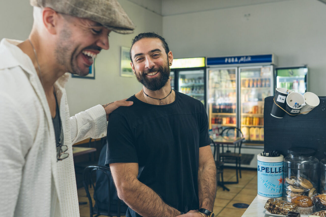 Cafe owner laughing with a customer at the counter, relaxed lifestyle brand photography in a Melbourne cafe.