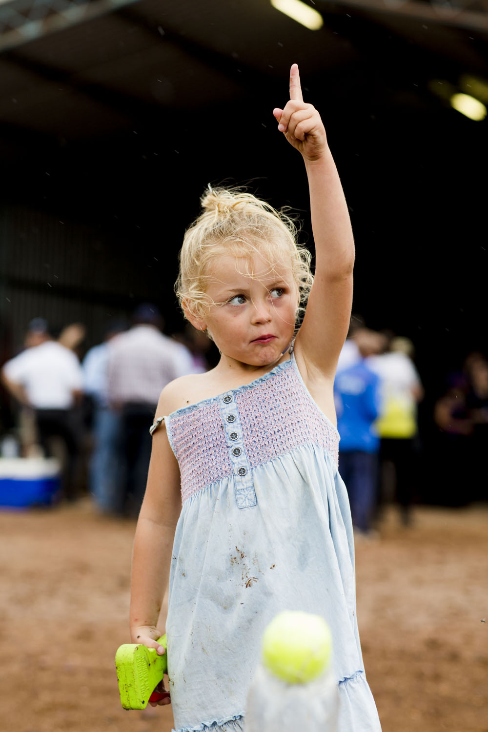 Young girl at a community event pointing upward with determination