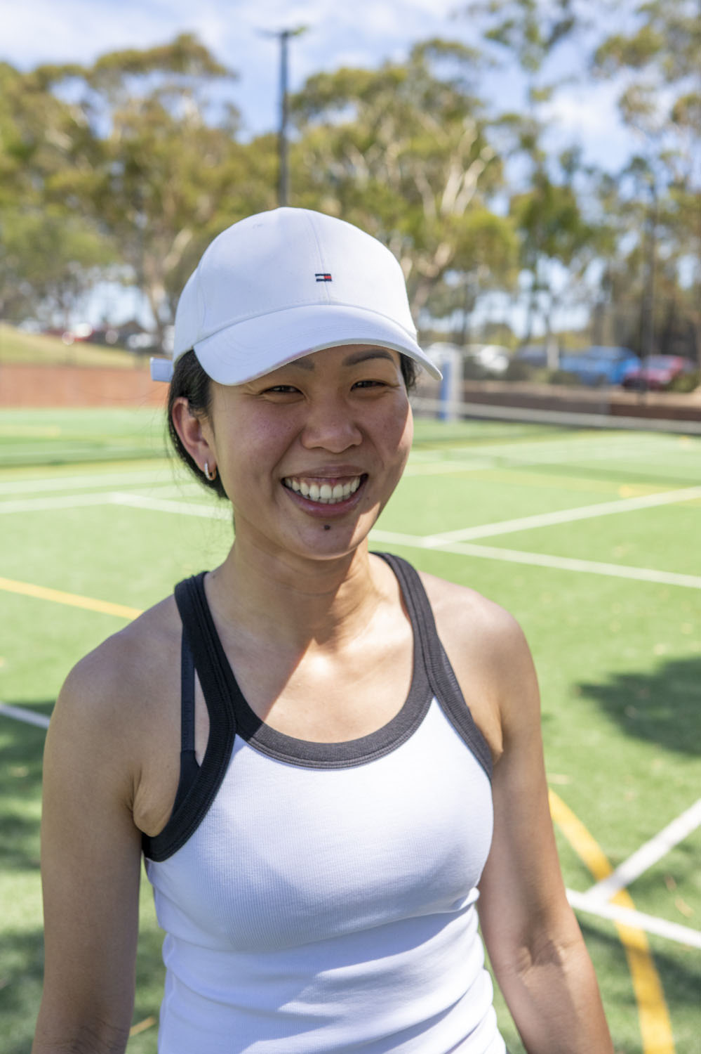 Authentic community campaign portrait of a local woman smiling on a tennis court in natural light