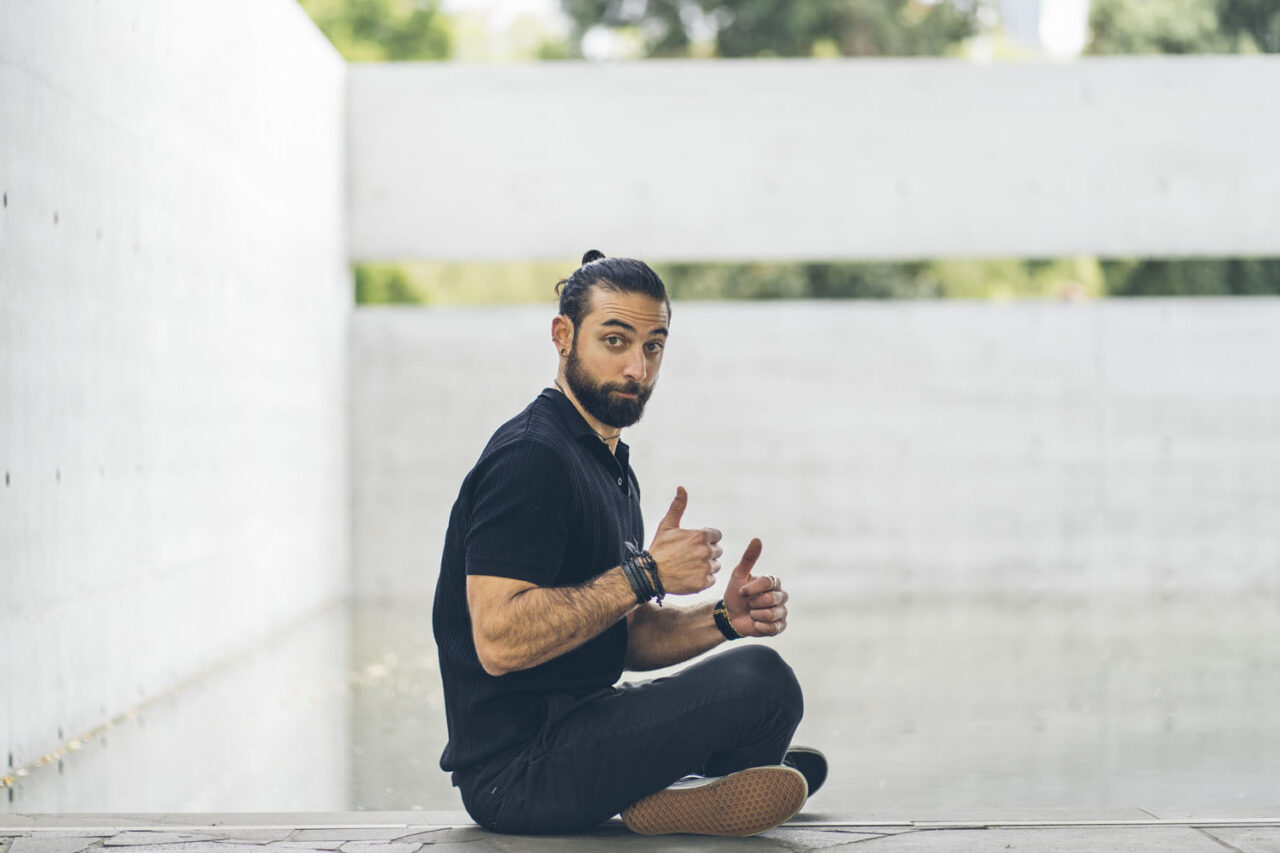 Relaxed documentary portrait of a man sitting casually in an urban outdoor space