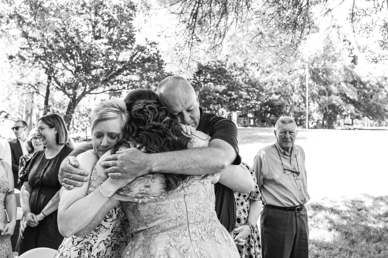 Family embracing the couple after the ceremony, emotional candid wedding photography
