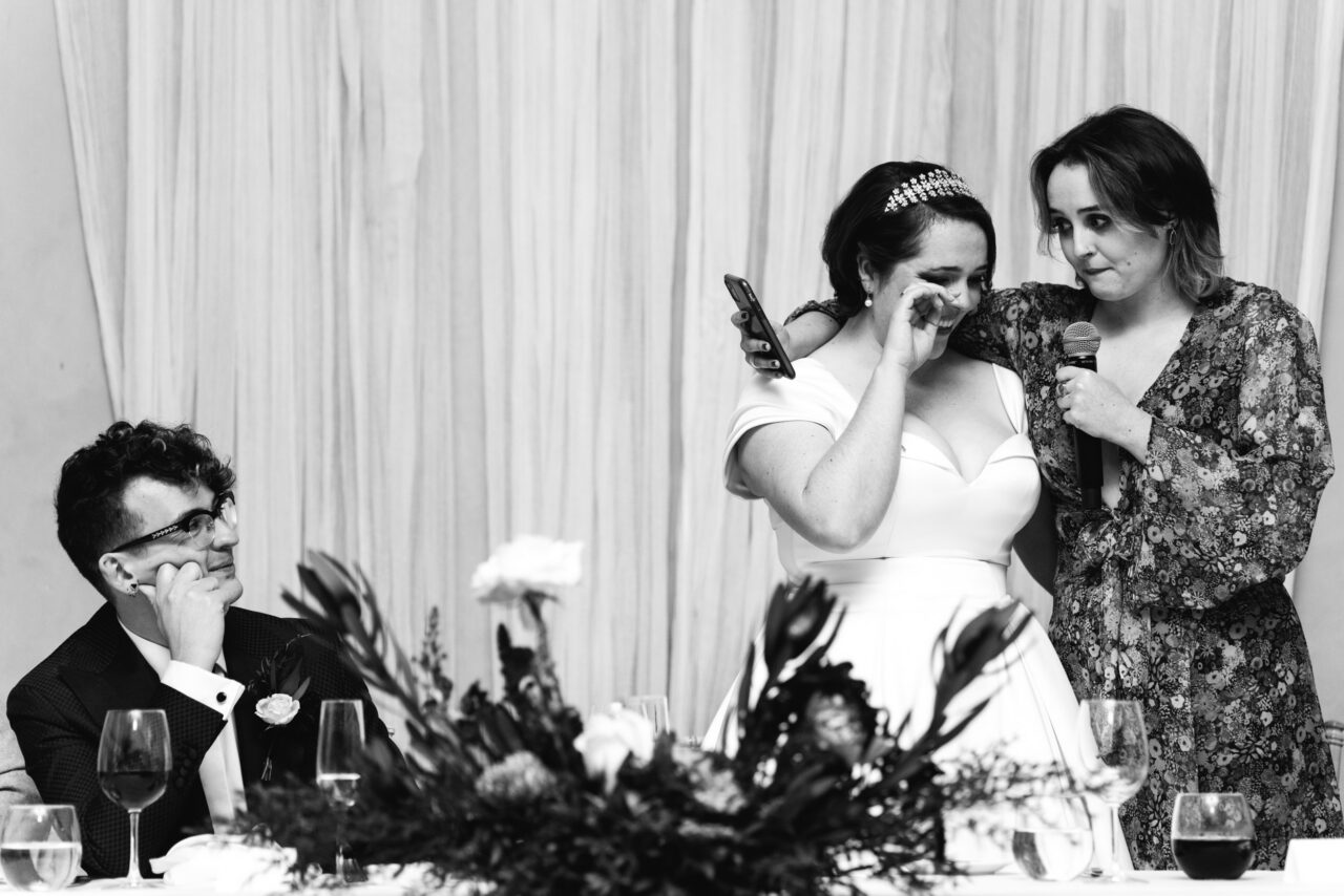 Partner wiping away tears during a heartfelt wedding speech at the reception