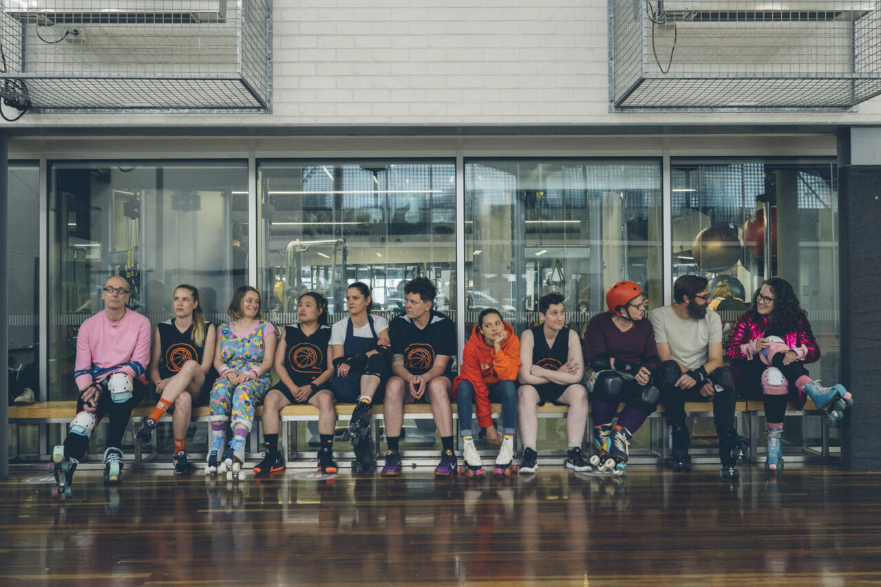 Inclusive roller skating team sitting together indoors during a community training session