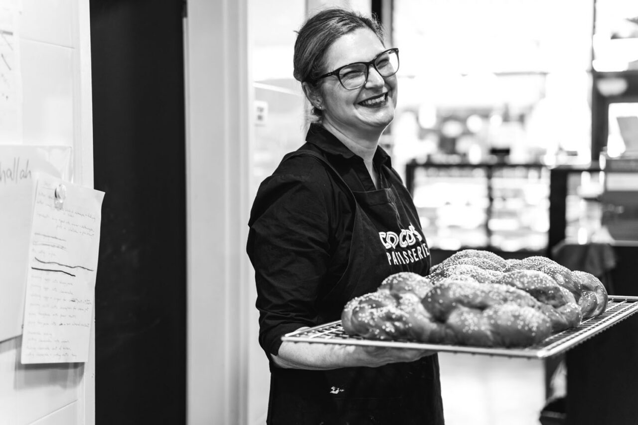 Documentary brand photography capturing a baker sharing fresh bread in her workspace