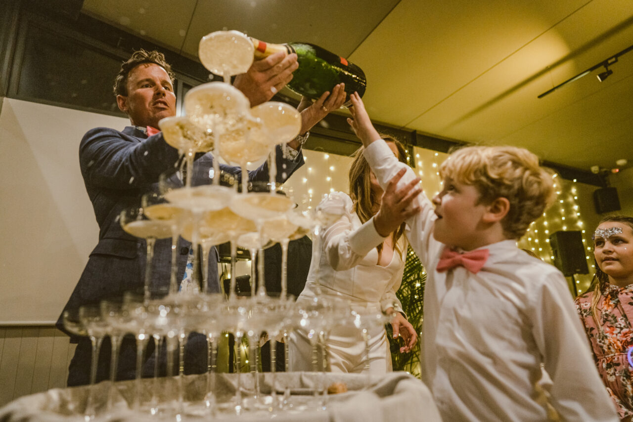 Children helping pour champagne tower at wedding reception