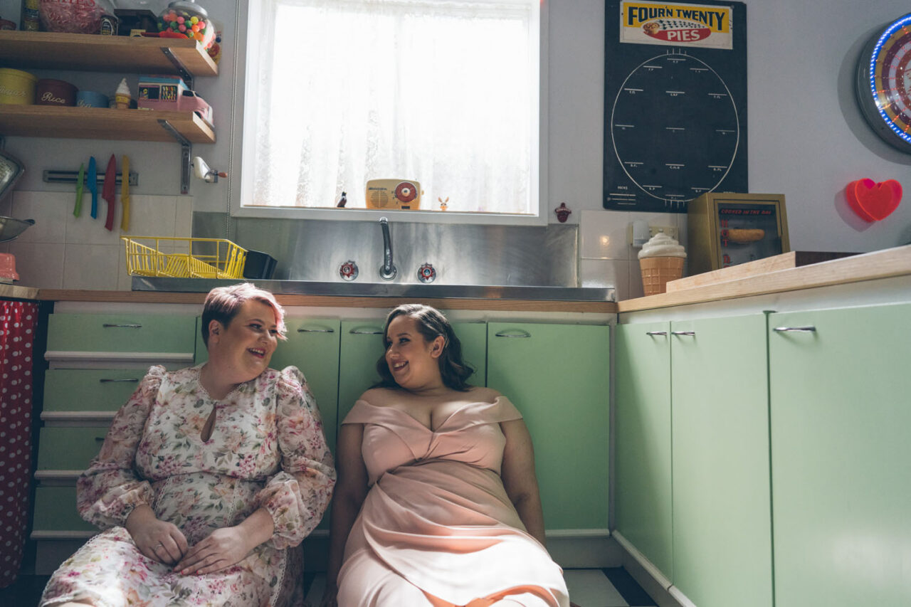 Two brides laughing together during their inclusive Surf Coast wedding.