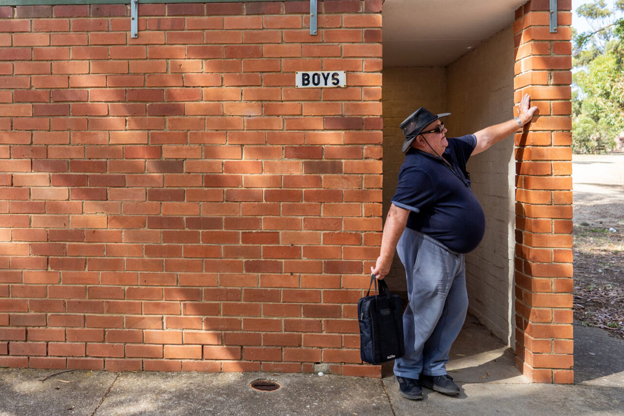 Older man standing outside a regional community facility building during a documentary photography session