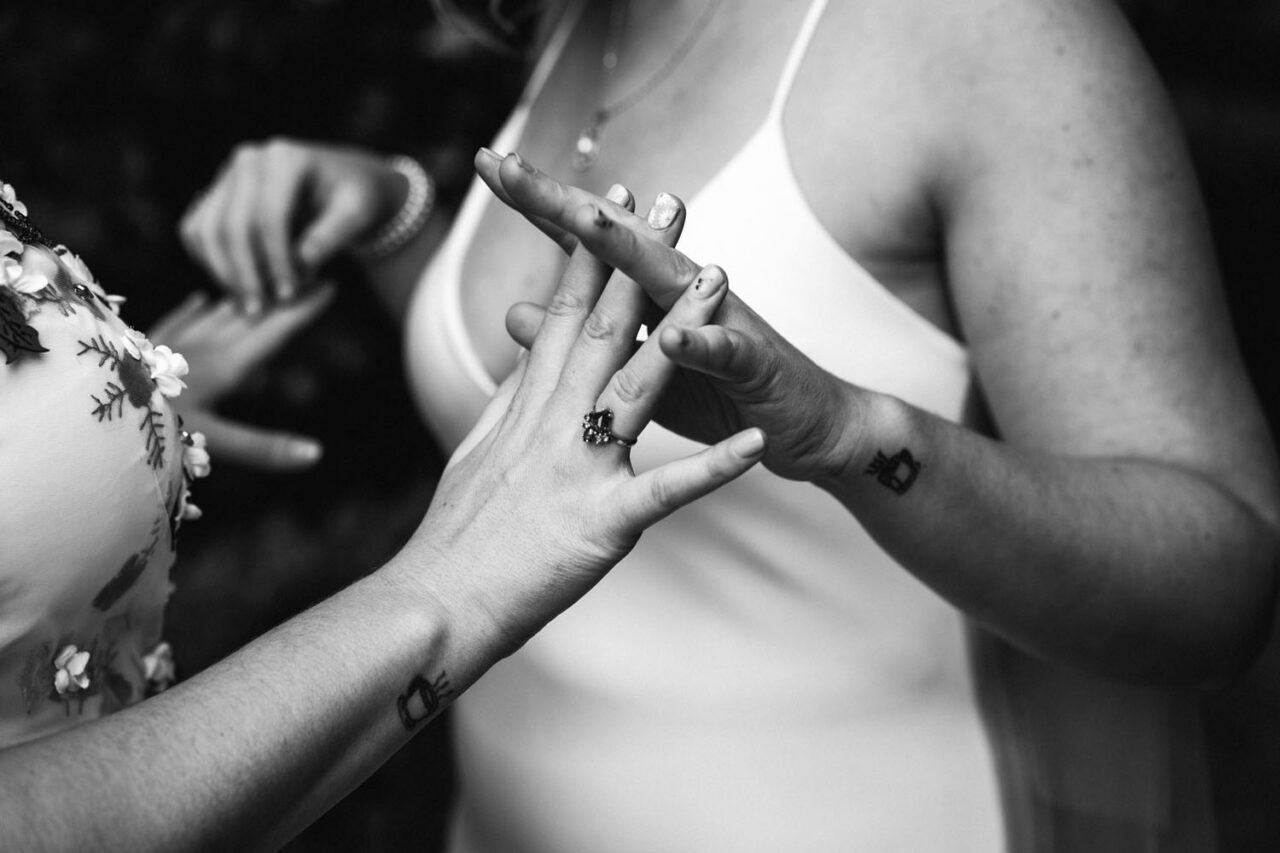 Close up of two brides holding hands and wedding rings