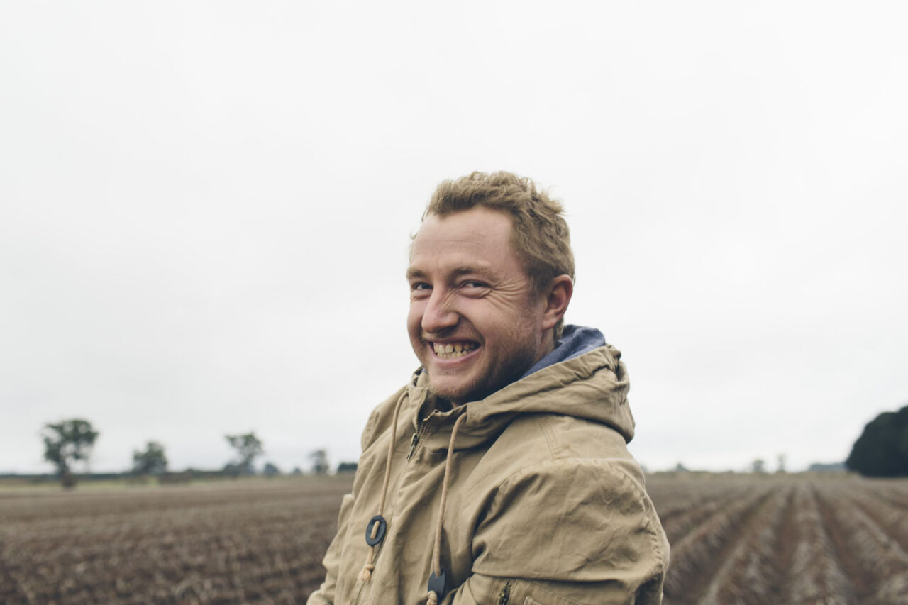 Smiling man standing in a rural field during a natural light brand portrait session