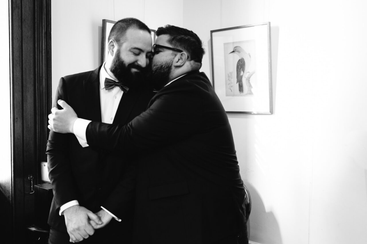 Two grooms sharing a quiet moment before their ceremony, emotional documentary wedding photography