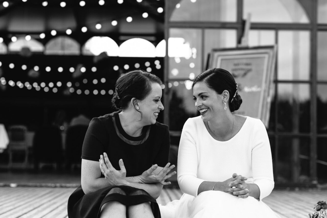Two women laughing together during the wedding reception, natural documentary style photography