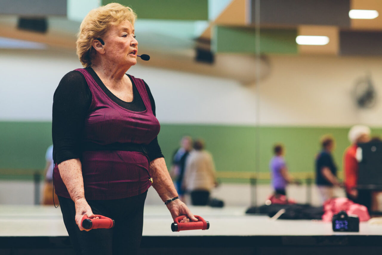 : Female fitness instructor leading a YMCA group exercise class with hand weights