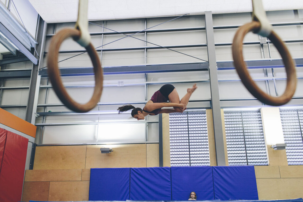 Young gymnast mid-air during YMCA gymnastics training session