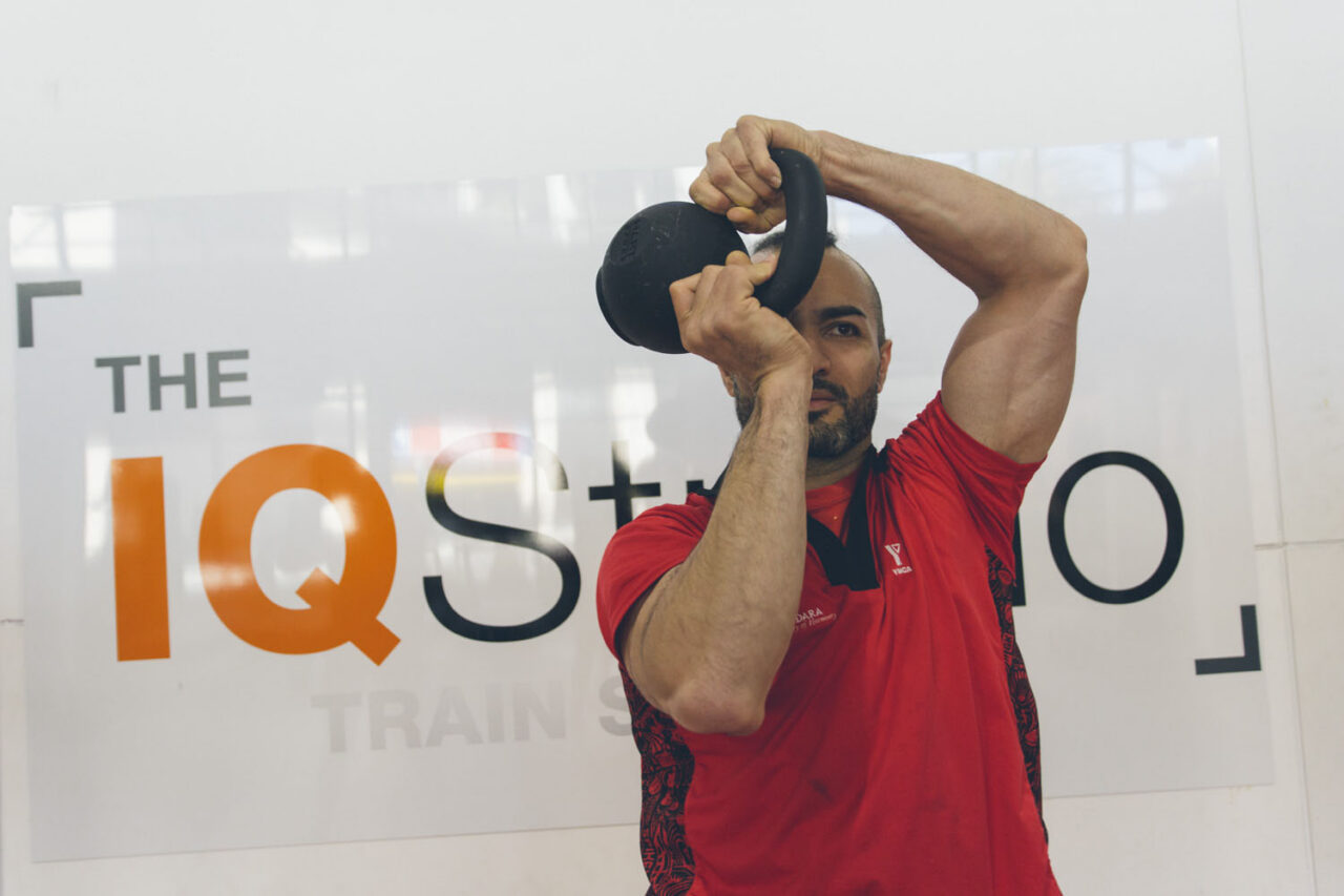 Personal trainer demonstrating a kettlebell exercise inside a YMCA training studio